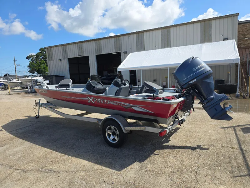 Slide: The Image of 2014 Xpress XP200 boat with Yamaha motor on trailer, parked outside a warehouse. - 7