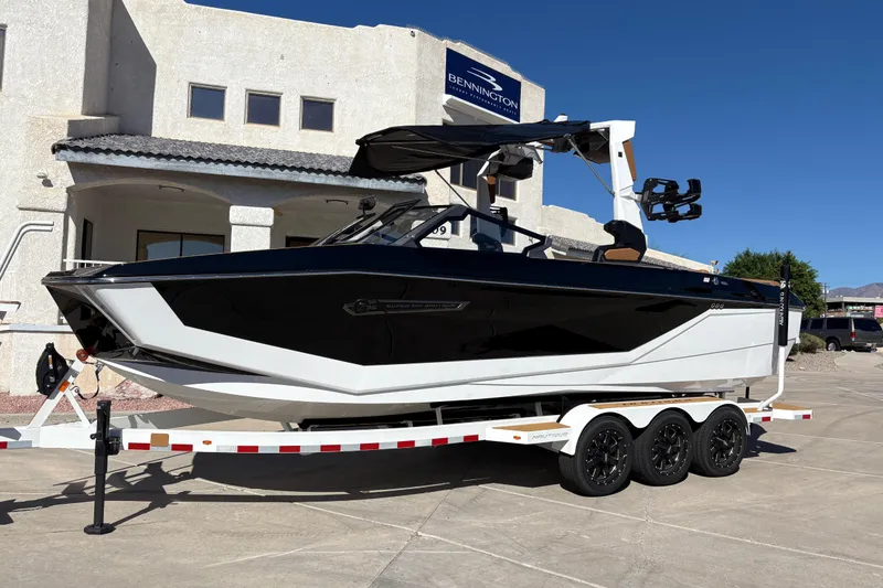 The Image of 2026 Nautique Super Air Nautique G25 boat on a trailer outside a building. - 0