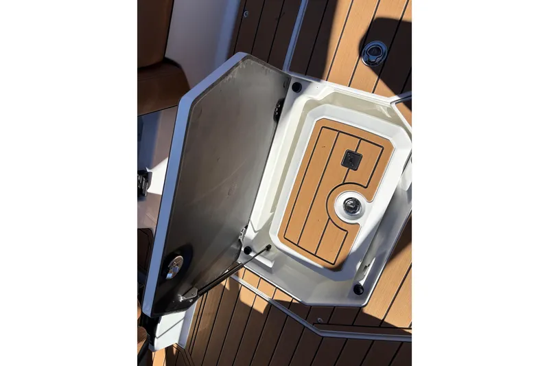 Slide: The Image of 2026 Nautique Super Air Nautique G25 storage compartment with teak flooring detail. - 17