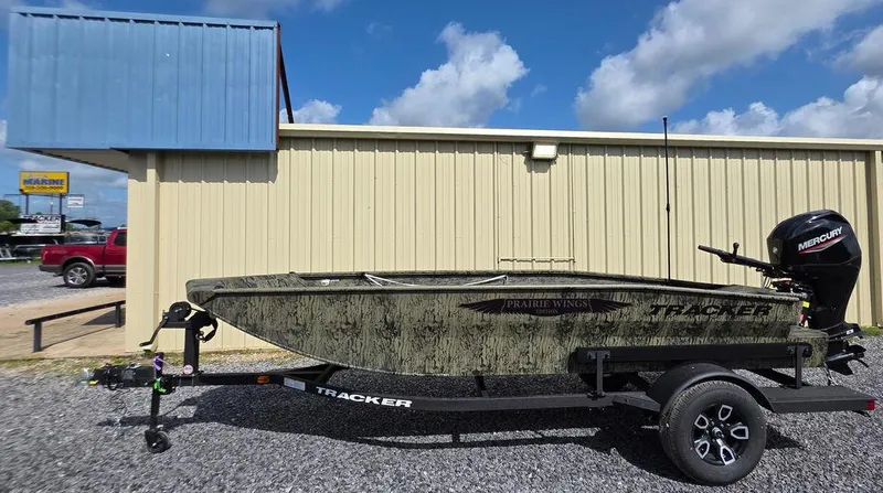 Slide: The Image of 2026 Tracker Grizzly® 1650 T Prairie Wings Edition boat on trailer, parked outside building. - 4