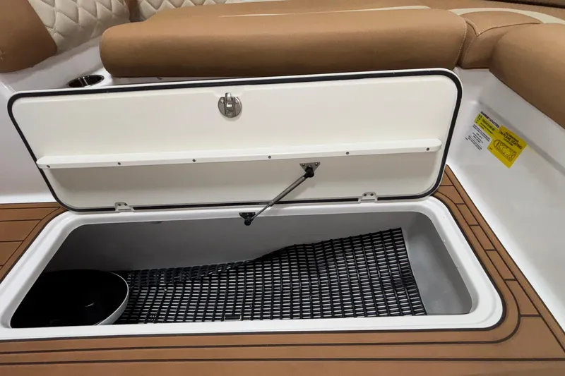 Slide: The Image of 2025 NauticStar 243 DC Deck boat storage compartment with cushioned seating and teak flooring. - 10