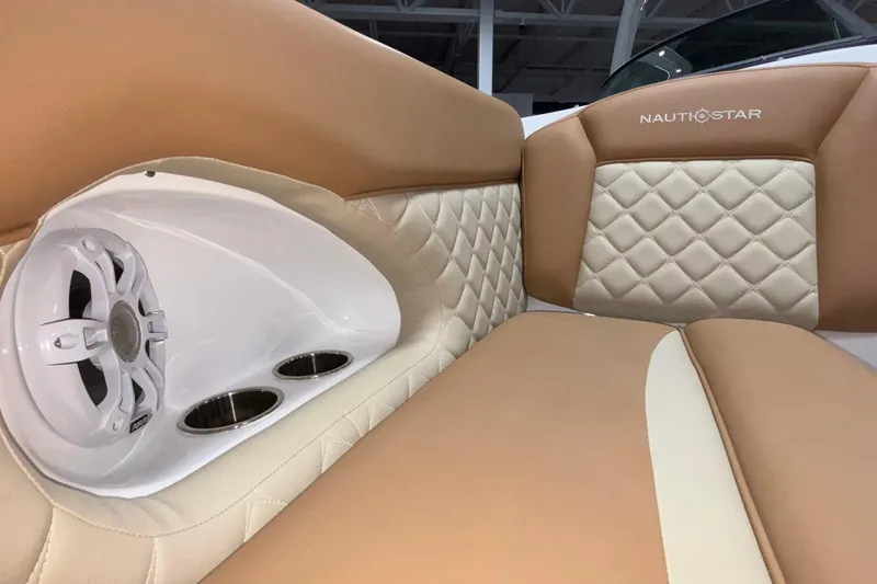 Slide: The Image of 2025 NauticStar 243 DC Deck boat interior with tan quilted seating and built-in speaker. - 11