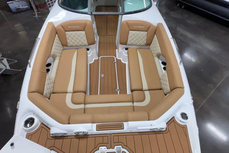 Slide: The Image of 2025 NauticStar 243 DC Deck boat interior with tan seating and wood-style flooring. - 17