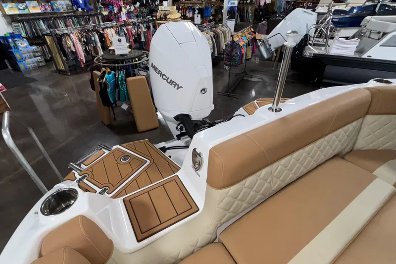 Slide: The Image of 2025 NauticStar 243 DC Deck boat interior with Mercury engine in showroom. - 19