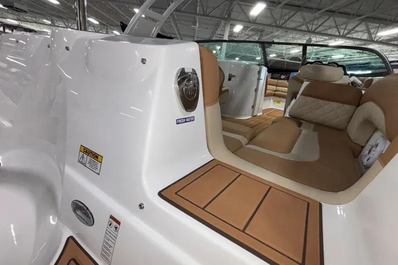Slide: The Image of 2025 NauticStar 243 DC Deck boat interior with tan seating and wood accents. - 20