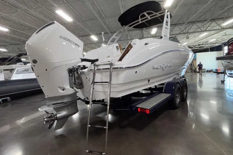 Slide: The Image of 2025 NauticStar 243 DC Deck boat with Mercury engine on trailer in showroom. - 24