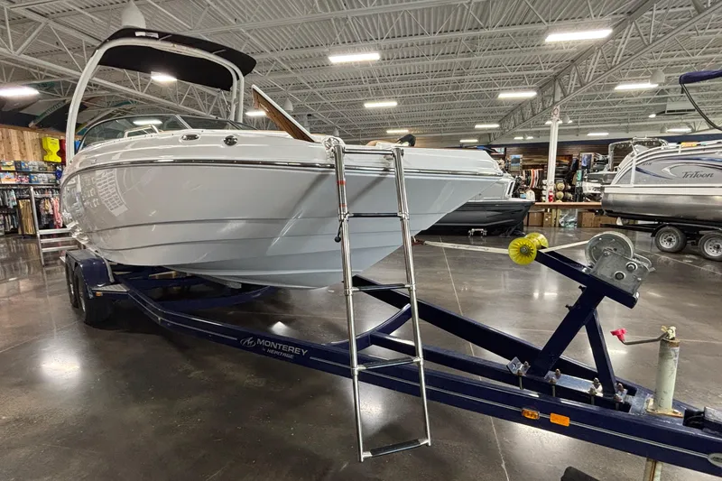 Slide: The Image of 2025 NauticStar 243 DC Deck boat on trailer in showroom setting. - 27