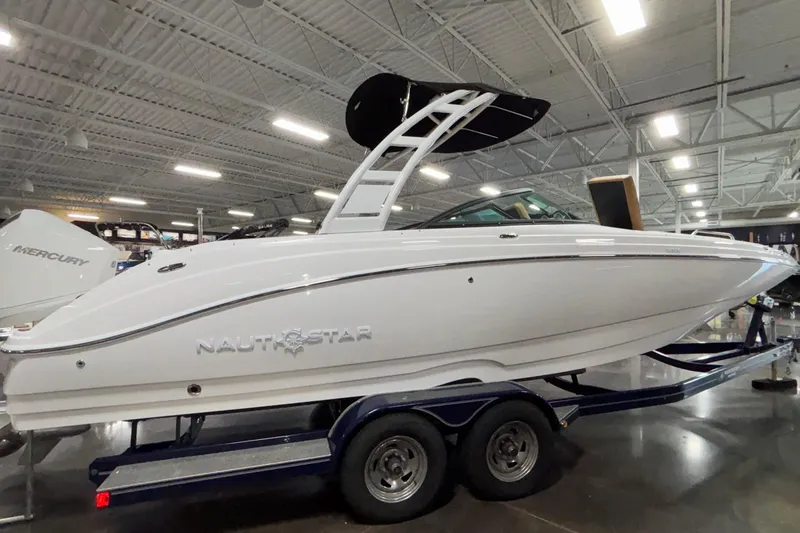 Slide: The Image of 2025 NauticStar 243 DC Deck boat displayed indoors on a trailer. - 8