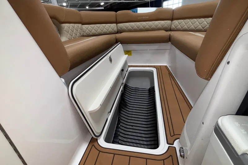 Slide: The Image of 2025 NauticStar 243 DC Deck boat interior with open storage compartment and cushioned seating. - 9
