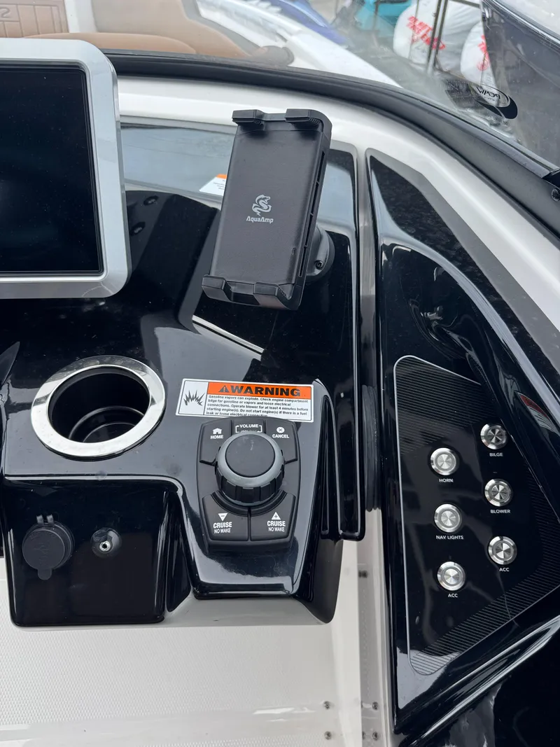 Slide: The Image of 2025 Yamaha Boats 252SD dashboard with controls, phone holder, and warning label. - 26