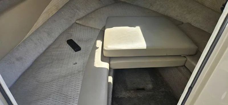 Slide: The Image of 2002 Bayliner 212 Capri Cuddy cabin interior with cushioned seating and carpeted flooring. - 7