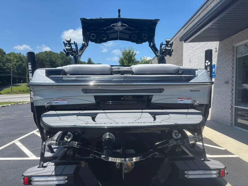 Slide: The Image of 2025 Centurion Ri245 boat rear view, parked outdoors under a clear blue sky. - 2