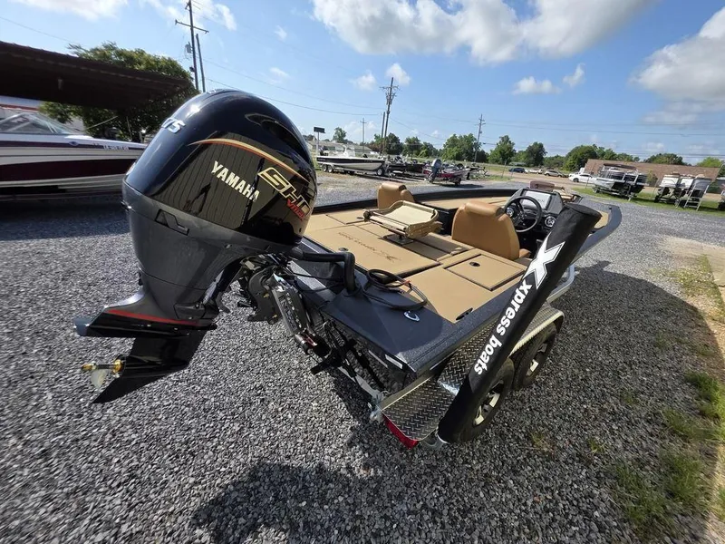 Slide: The Image of 2026 Xpress H20C boat with Yamaha engine, parked on gravel under a clear sky. - 13
