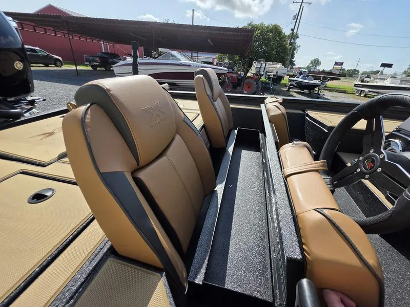 Slide: The Image of 2026 Xpress H20C boat interior with tan seats and steering wheel, parked outdoors. - 17