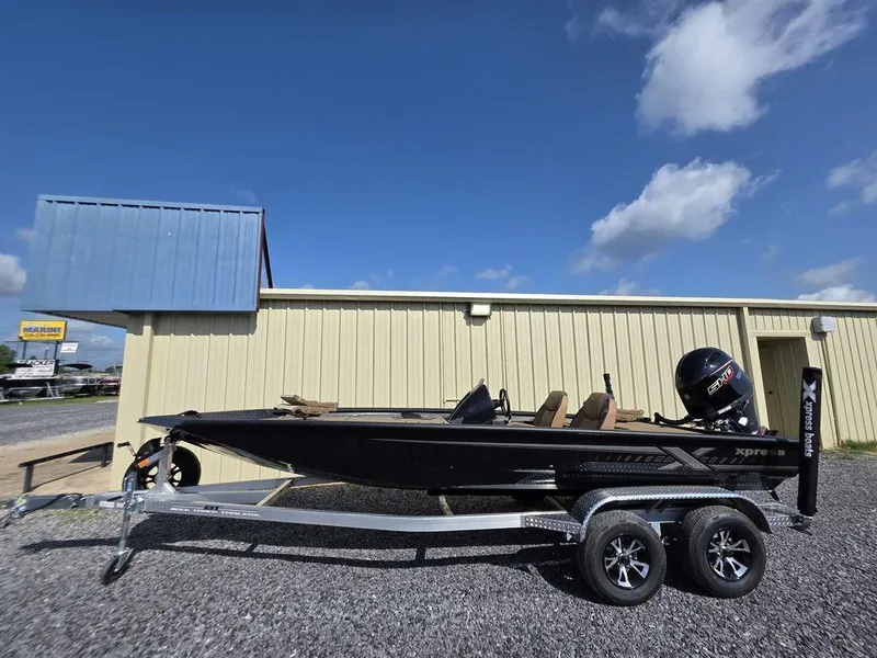 Slide: The Image of 2026 Xpress H20C boat on trailer, parked outside a beige building under a clear blue sky. - 3