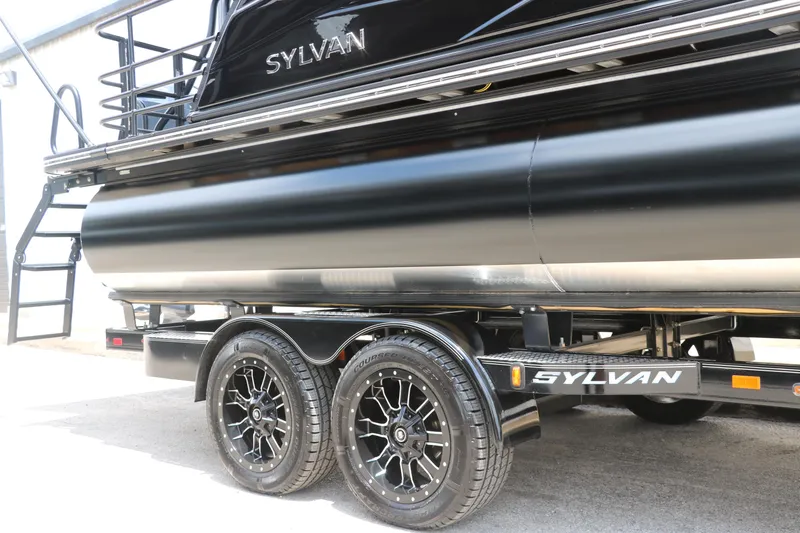 Slide: The Image of 2026 Sylvan G3 DLZ Bar pontoon boat on trailer, featuring sleek black design and dual wheels. - 13