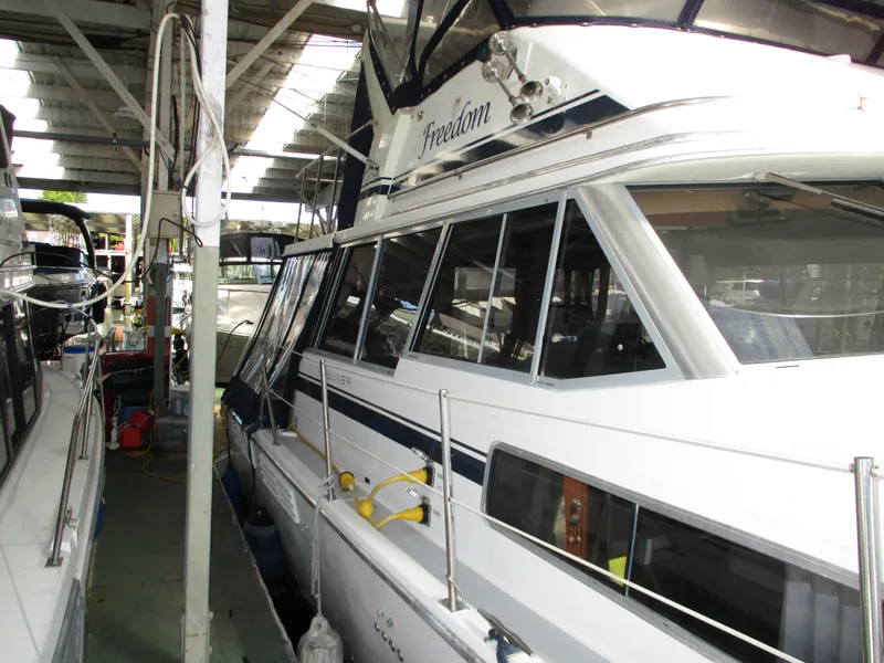 Slide: The Image of 1989 Bayliner 3888 yacht docked in a covered marina, showcasing its sleek design and windows. - 11