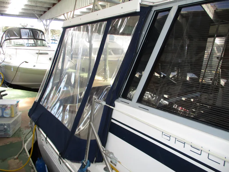 Slide: The Image of 1989 Bayliner 3888 yacht with clear enclosure, docked in a covered marina. - 2