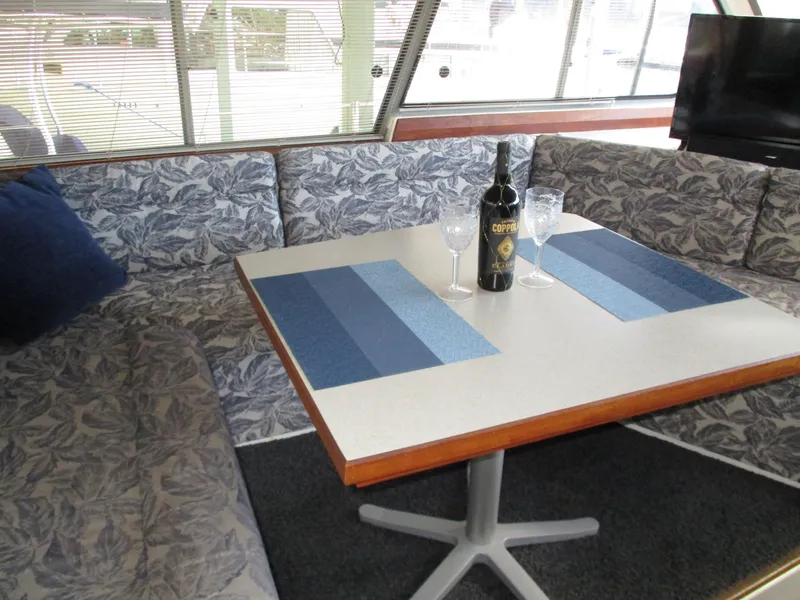 Slide: The Image of Interior of 1989 Bayliner 3888 with dining table, wine bottle, and glasses. - 24