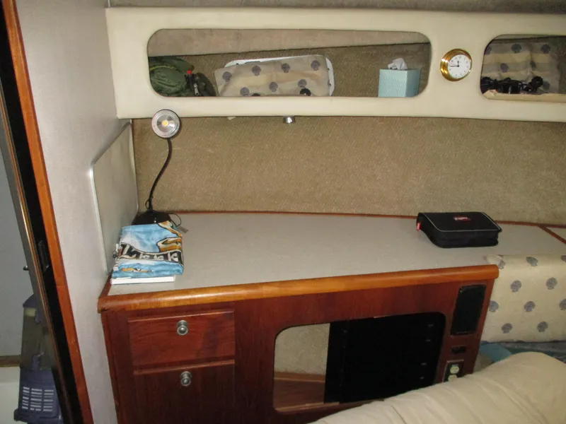 Slide: The Image of 1989 Bayliner 3888 cabin interior with wooden desk, storage, and nautical decor. - 34