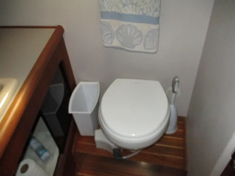 Slide: The Image of 1989 Bayliner 3888 yacht bathroom with toilet, wooden flooring, and shell-patterned towel. - 39