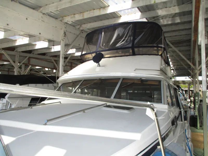 Slide: The Image of 1989 Bayliner 3888 yacht docked in a covered marina, showcasing its sleek design. - 7