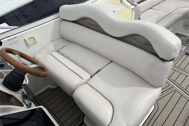 Slide: The Image of 2002 Doral 330se boat interior with white leather seating and wooden steering wheel. - 10