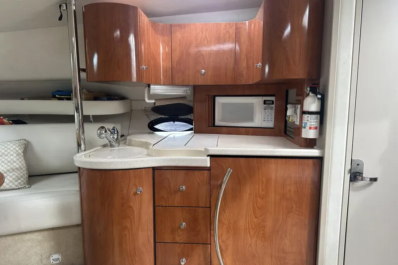 Slide: The Image of 2002 Doral 330se boat interior with wooden cabinets, sink, and microwave. - 18