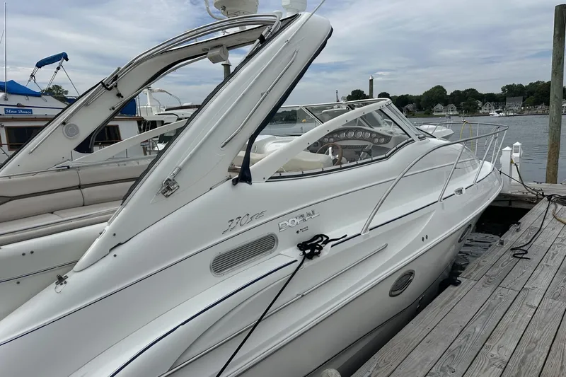 Slide: The Image of 2002 Doral 330se boat docked at marina, featuring sleek white design and spacious deck. - 3