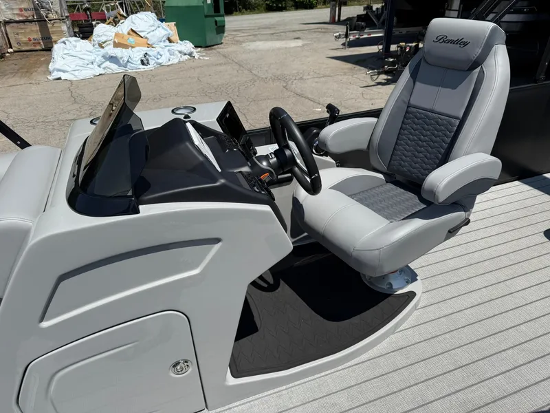 Slide: The Image of 2026 Bentley Pontoons Elite 253 Swingback helm with luxurious captain's chair and sleek dashboard. - 5