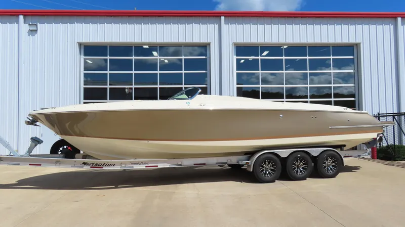 Slide: The Image of 2018 Chris-Craft Launch 34 boat on trailer, parked outside a building with large windows. - 1