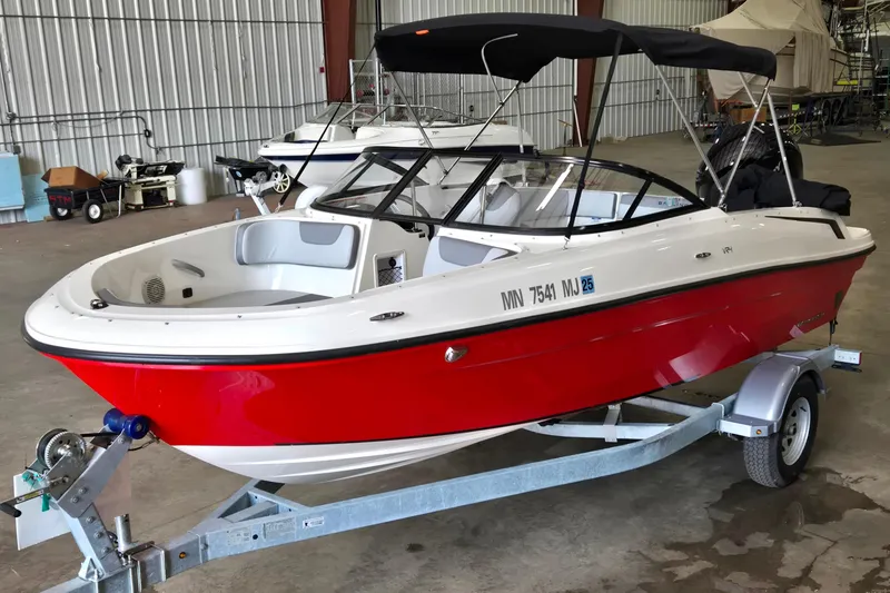 The Image of 2023 Bayliner VR4 Bowrider OB in a warehouse, red and white design on a trailer. - 0