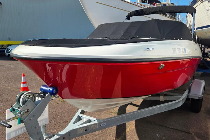 Slide: The Image of 2023 Bayliner VR4 Bowrider OB in red, covered, on a trailer. - 2