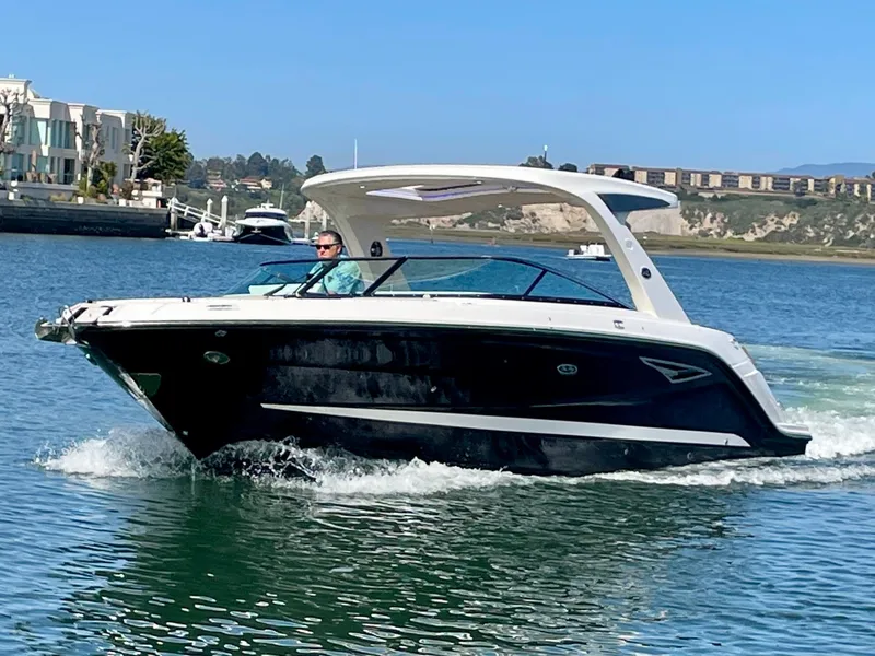Slide: The Image of 2019 Sea Ray SLX 310 boat cruising on a sunny day in a scenic harbor. - 2