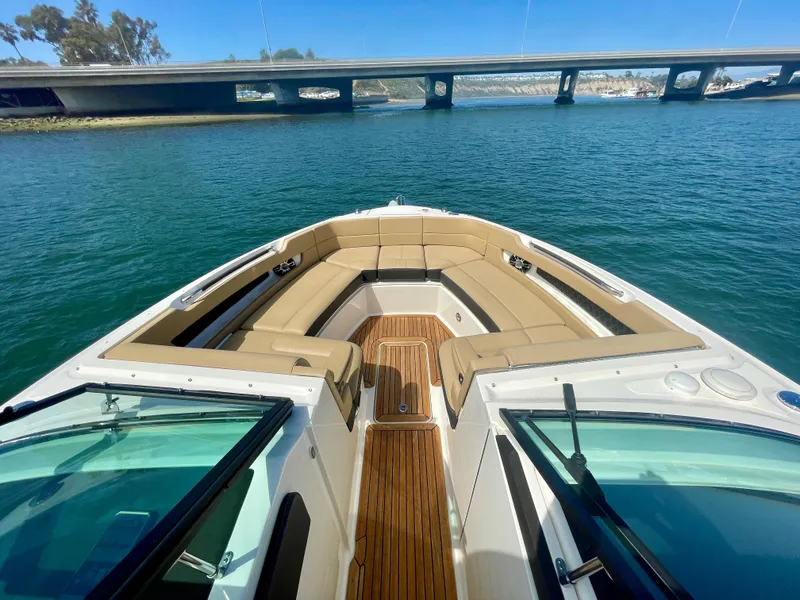 Slide: The Image of 2019 Sea Ray SLX 310 boat with spacious seating, cruising under a bridge on calm waters. - 23