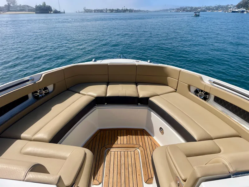 Slide: The Image of 2019 Sea Ray SLX 310 boat with tan seating and wooden deck on calm water. - 24