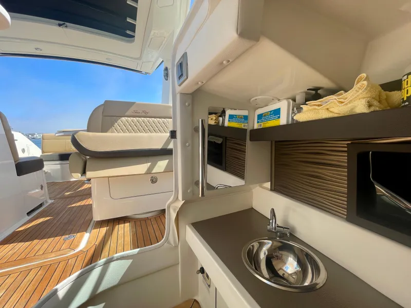 Slide: The Image of 2019 Sea Ray SLX 310 interior with kitchenette, sink, and seating area. - 29