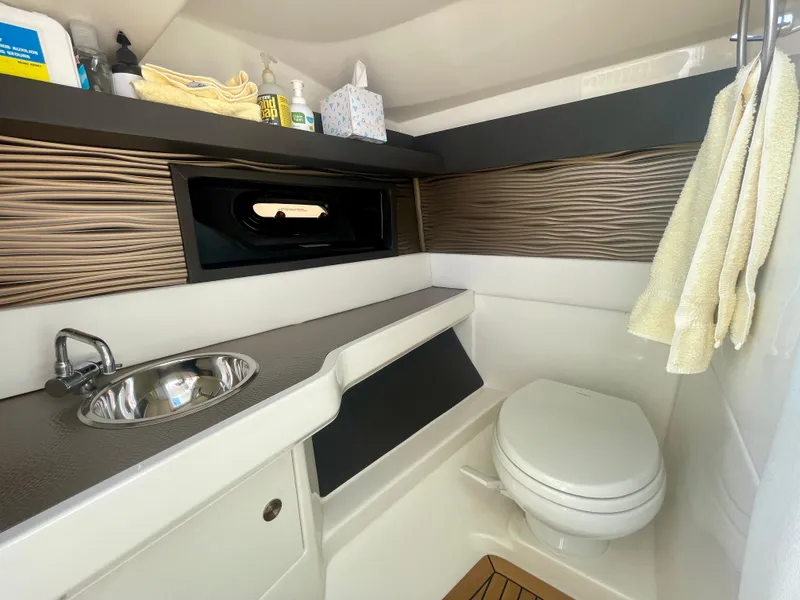 Slide: The Image of 2019 Sea Ray SLX 310 boat bathroom with sink, toilet, and storage shelves. - 30