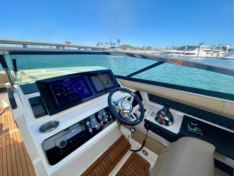 Slide: The Image of 2019 Sea Ray SLX 310 helm with modern controls and scenic marina view. - 34