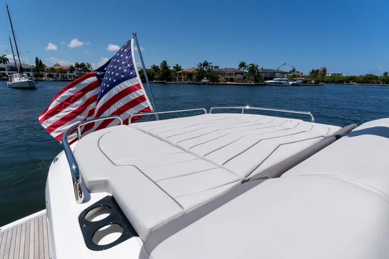 Slide: The Image of Sunseeker Predator 60 yacht, 2022 model, with American flag, on a sunny day by the water. - 18