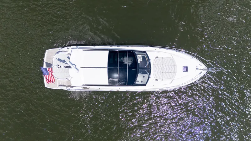 Slide: The Image of Aerial view of 2022 Sunseeker Predator 60 yacht on water, displaying sleek design and American flag. - 6