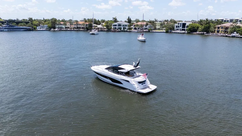 Slide: The Image of 2022 Sunseeker Predator 60 yacht cruising on a calm waterway, surrounded by luxury homes. - 7