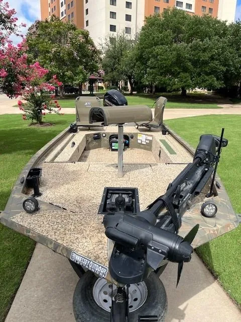 Slide: The Image of 2023 Tracker 1654SPT boat on a trailer, parked outdoors near trees and buildings. - 7