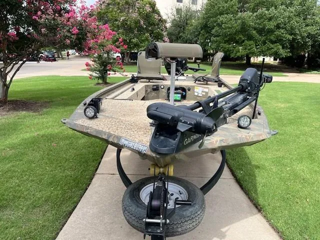 Slide: The Image of 2023 Tracker 1654SPT boat on trailer, parked on grass with trees in background. - 8