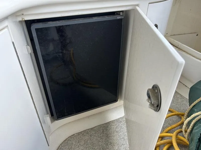 Slide: The Image of Open cabinet on 2002 Sea Ray 290 boat, revealing a Norcold refrigerator inside. - 12