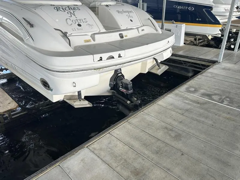 Slide: The Image of 2002 Sea Ray 290 boat docked, rear view showing outboard motor and platform. - 3