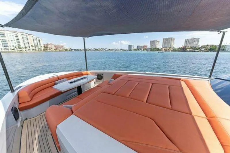 Slide: The Image of Luxurious 2021 Vanquish VQ58 yacht with orange seating, shaded deck, and waterfront city view. - 29