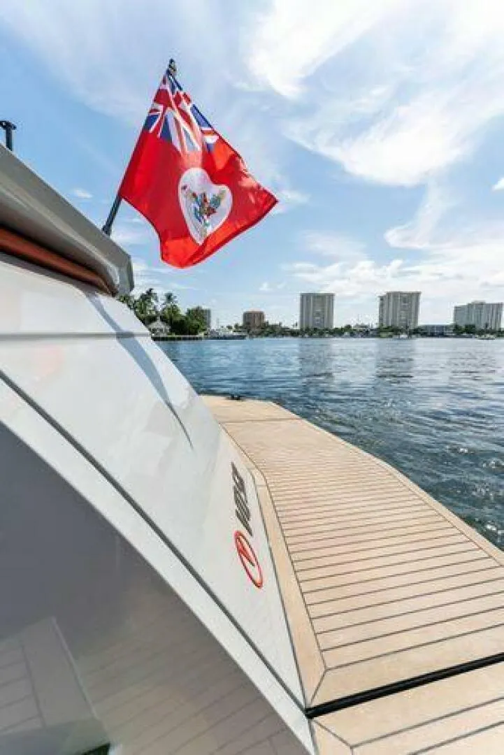 Slide: The Image of Luxury Vanquish VQ58 yacht with red flag, docked by waterfront cityscape, 2021 model. - 38