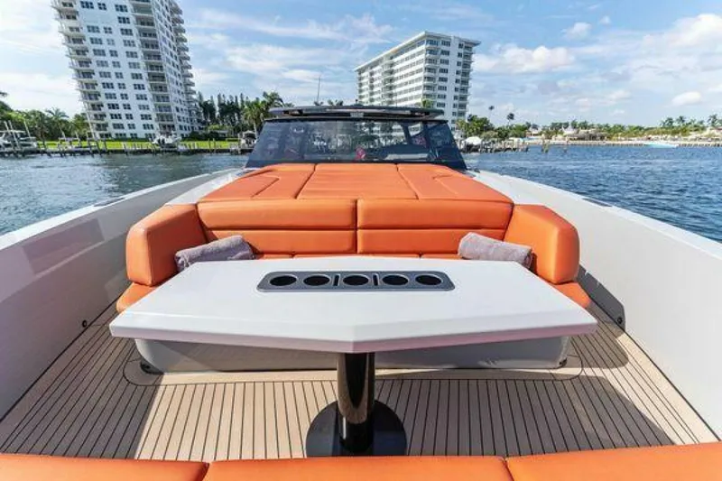 Slide: The Image of Vanquish VQ58 2021 luxury yacht with orange seating and table, docked near waterfront buildings. - 7