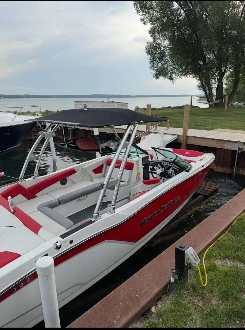 Slide: The Image of 2017 MasterCraft NXT22 boat docked by a scenic lakeside with lush greenery. - 3